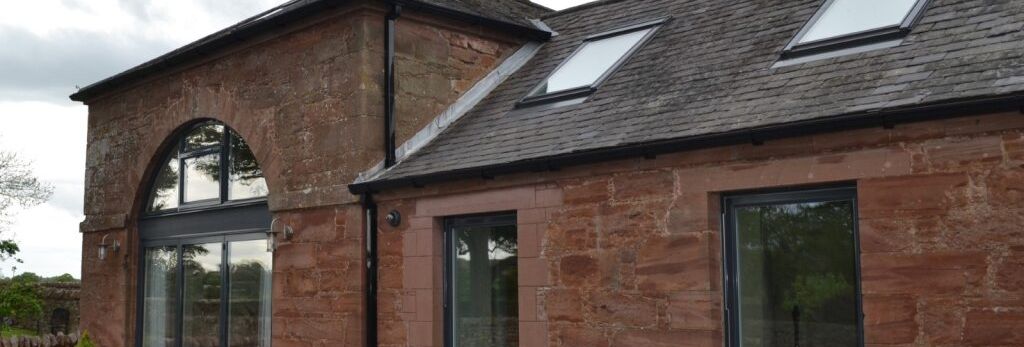 Stone building with large windows and skylights, modern landscaping