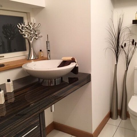 Modern bathroom with vessel sink, decorative bottles, and metallic branch ornament