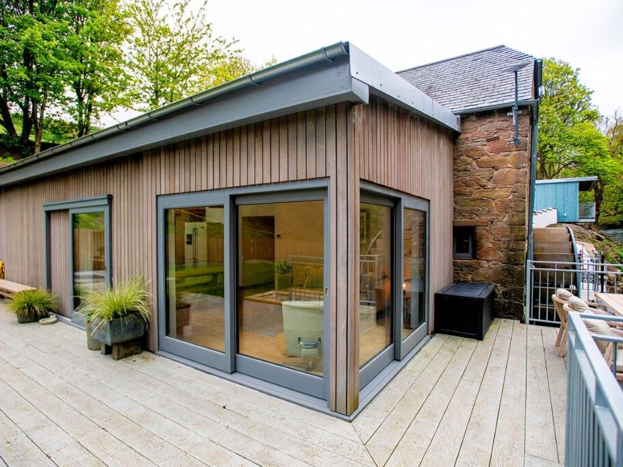 Modern wooden house with large windows and spacious patio area