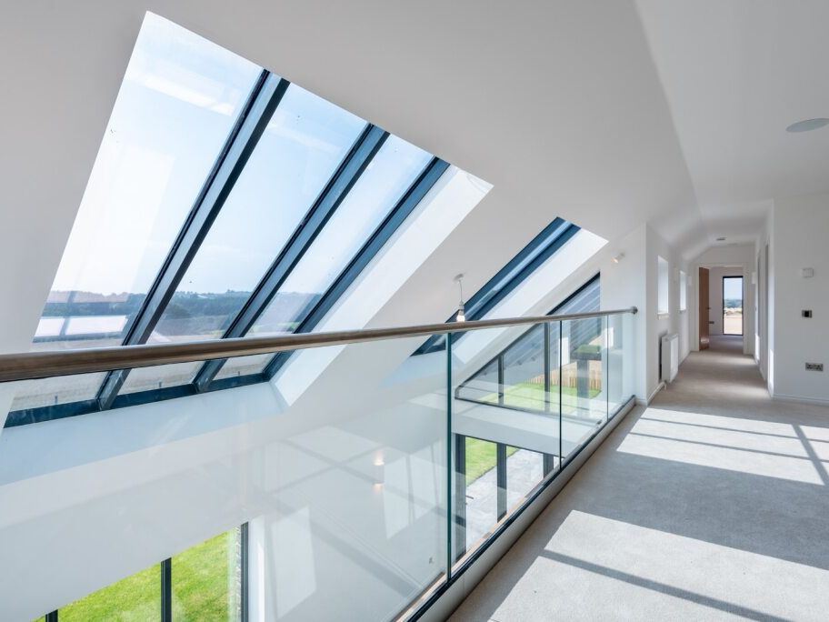 Modern hallway with large slanted glass windows and glass railing