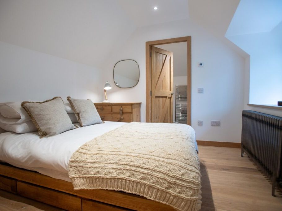 Cozy bedroom with a double bed, wooden flooring, and a rustic wooden door
