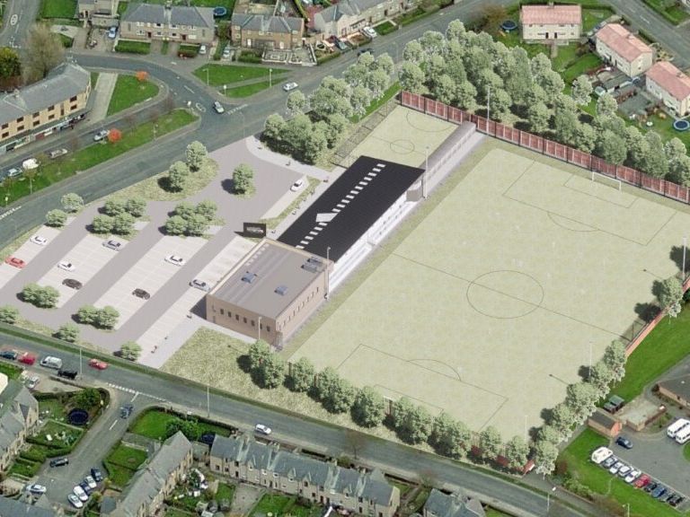 Aerial view of a football stadium complex with parking lot and adjacent buildings