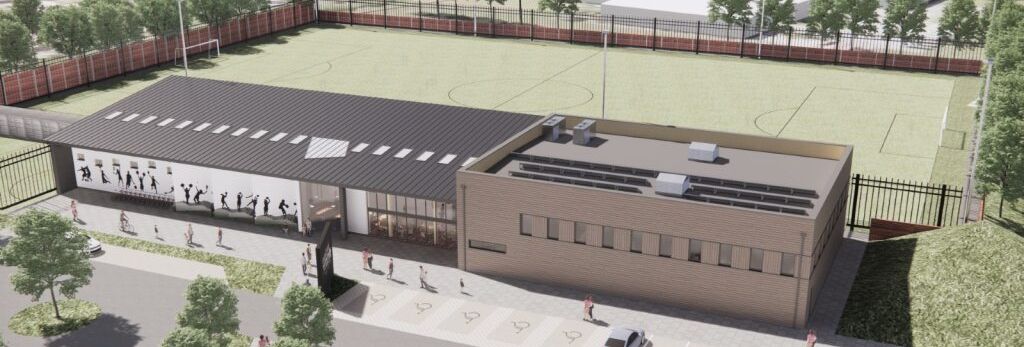 Aerial view of a modern sports facility with adjacent football fields and parking lot