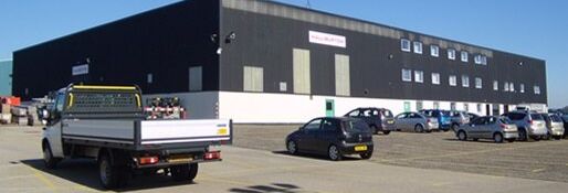 Industrial warehouse building with parked vehicles in parking lot