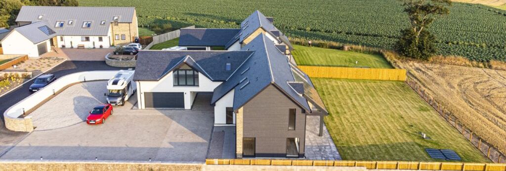 Aerial view of modern houses with well-maintained lawns and farmland in the background