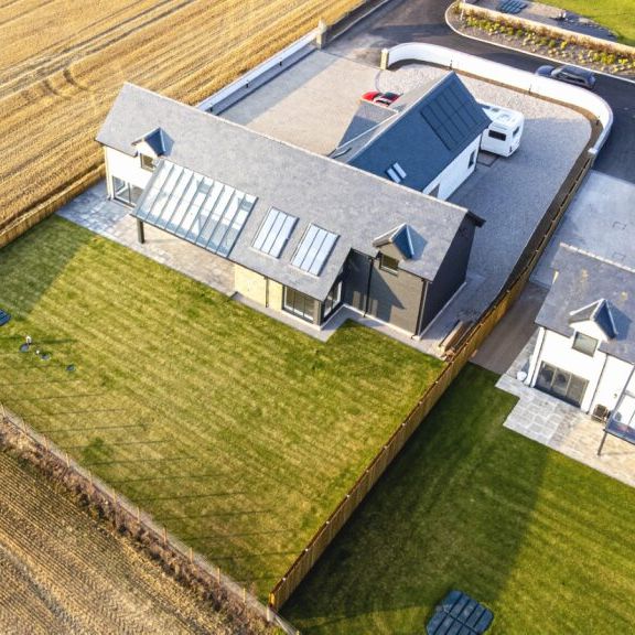 Aerial view of modern houses with large green lawns next to farmland