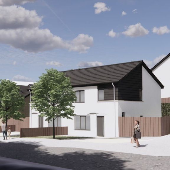 Modern residential neighborhood with white detached and semi-detached houses, trees, fences, and people walking on the street under a partly cloudy sky.