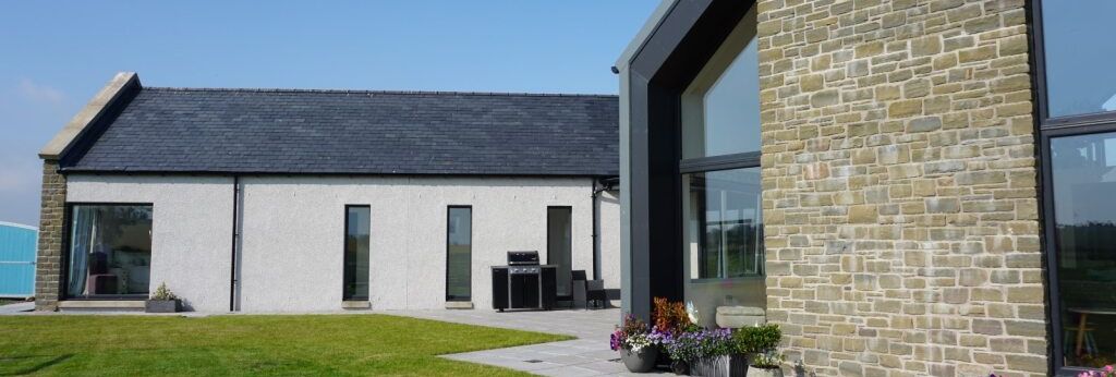 Modern house with brick and glass exterior, large lawn, and potted flowers.