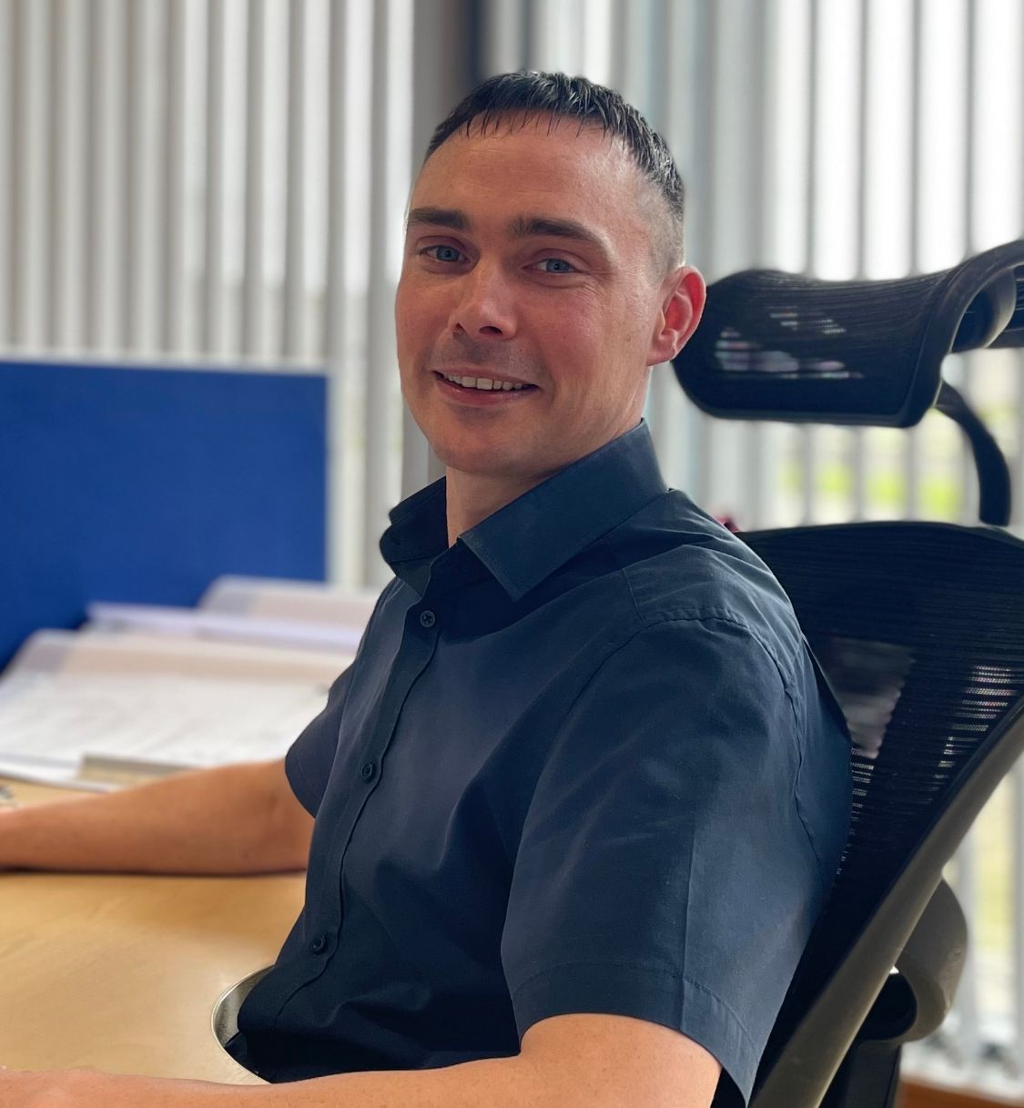 Person sitting at an office desk with papers and architectural drawings