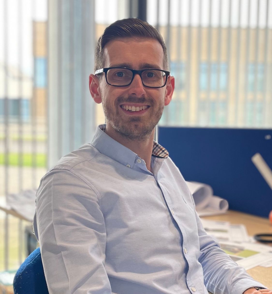 Man with glasses sitting at a desk in an office