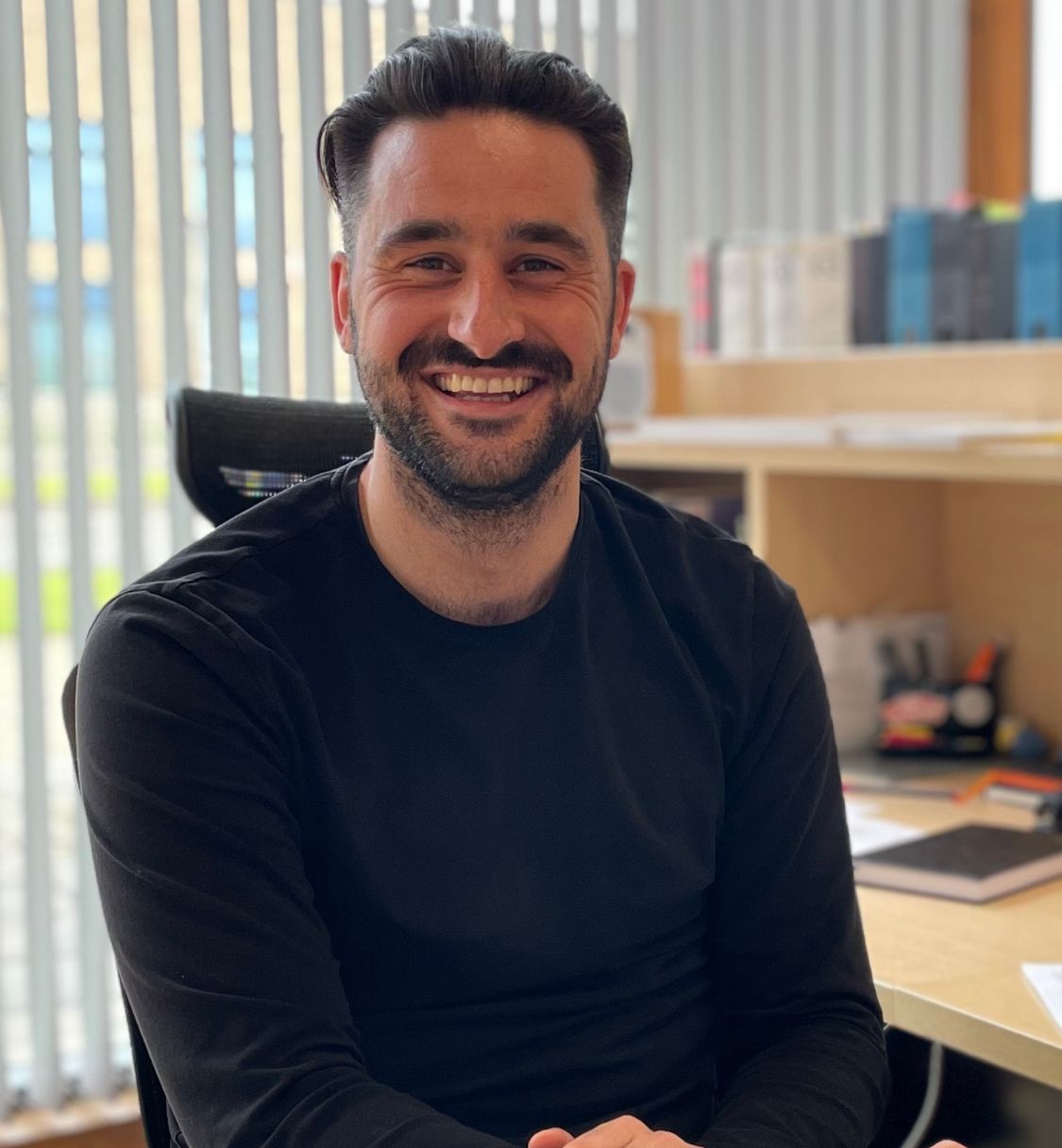 Smiling man sitting at a desk in an office setting