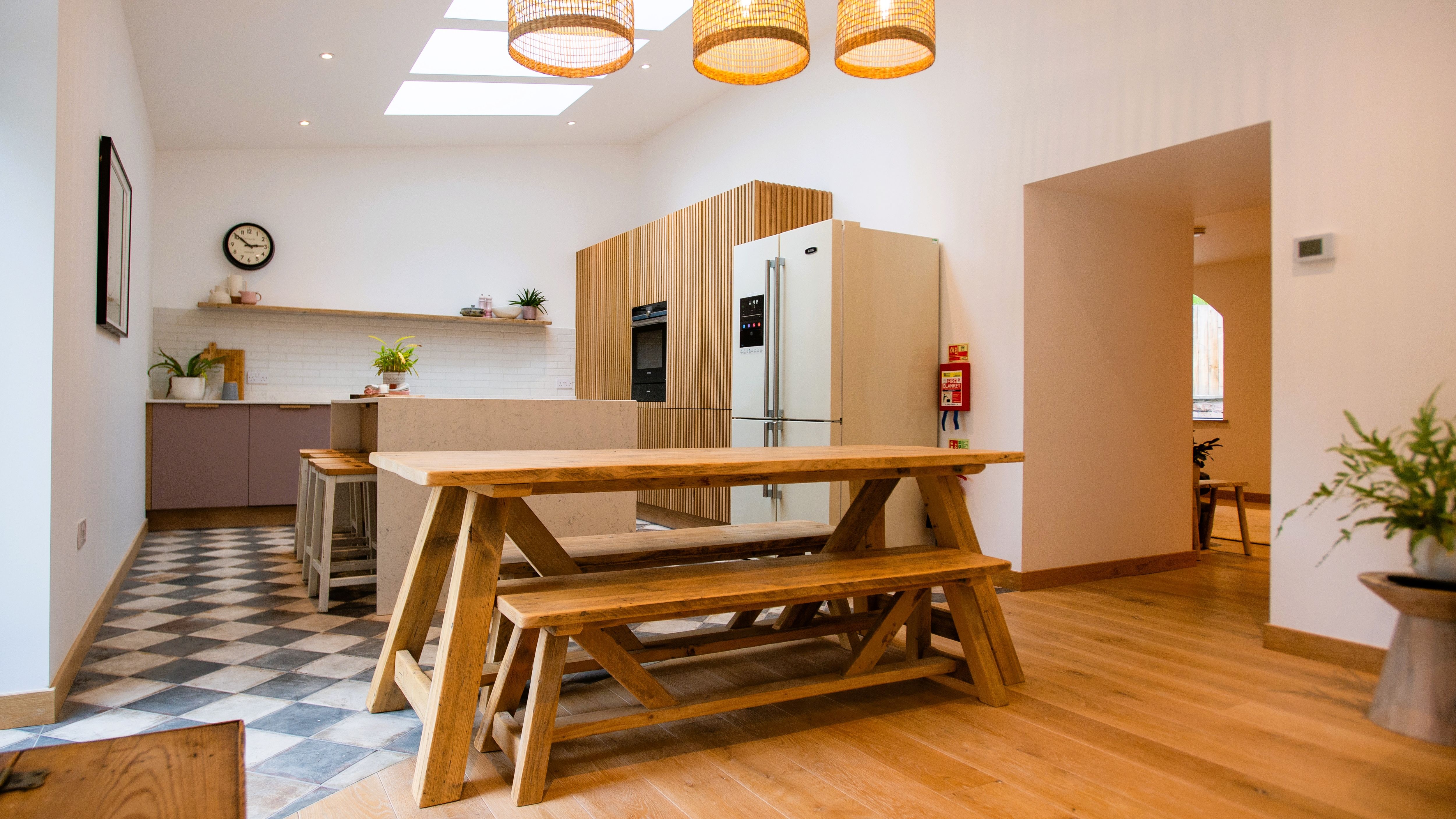Modern open-plan kitchen and dining area with wooden furniture and pendant lights