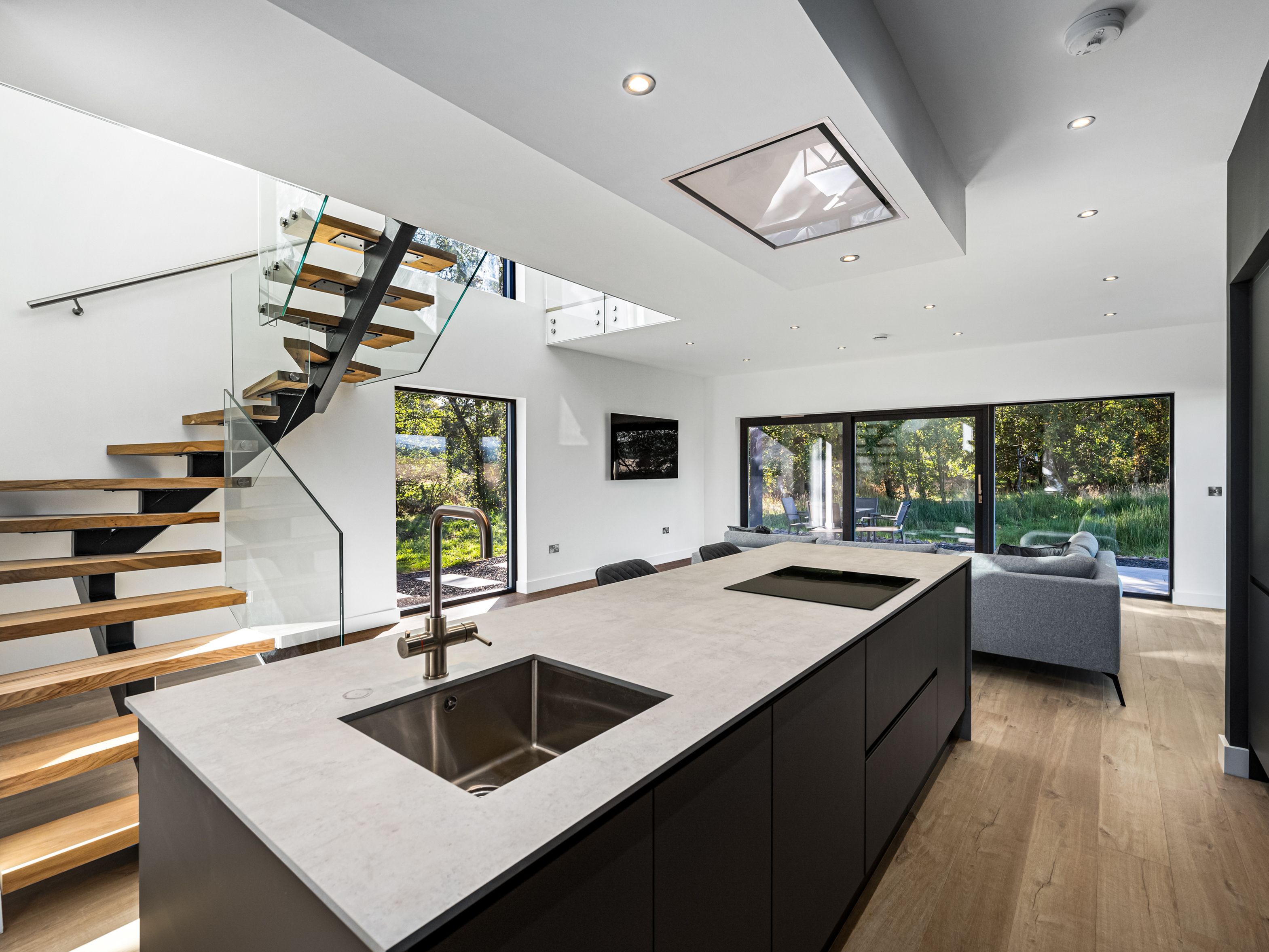 Modern open-plan kitchen and living area with large windows and a floating staircase