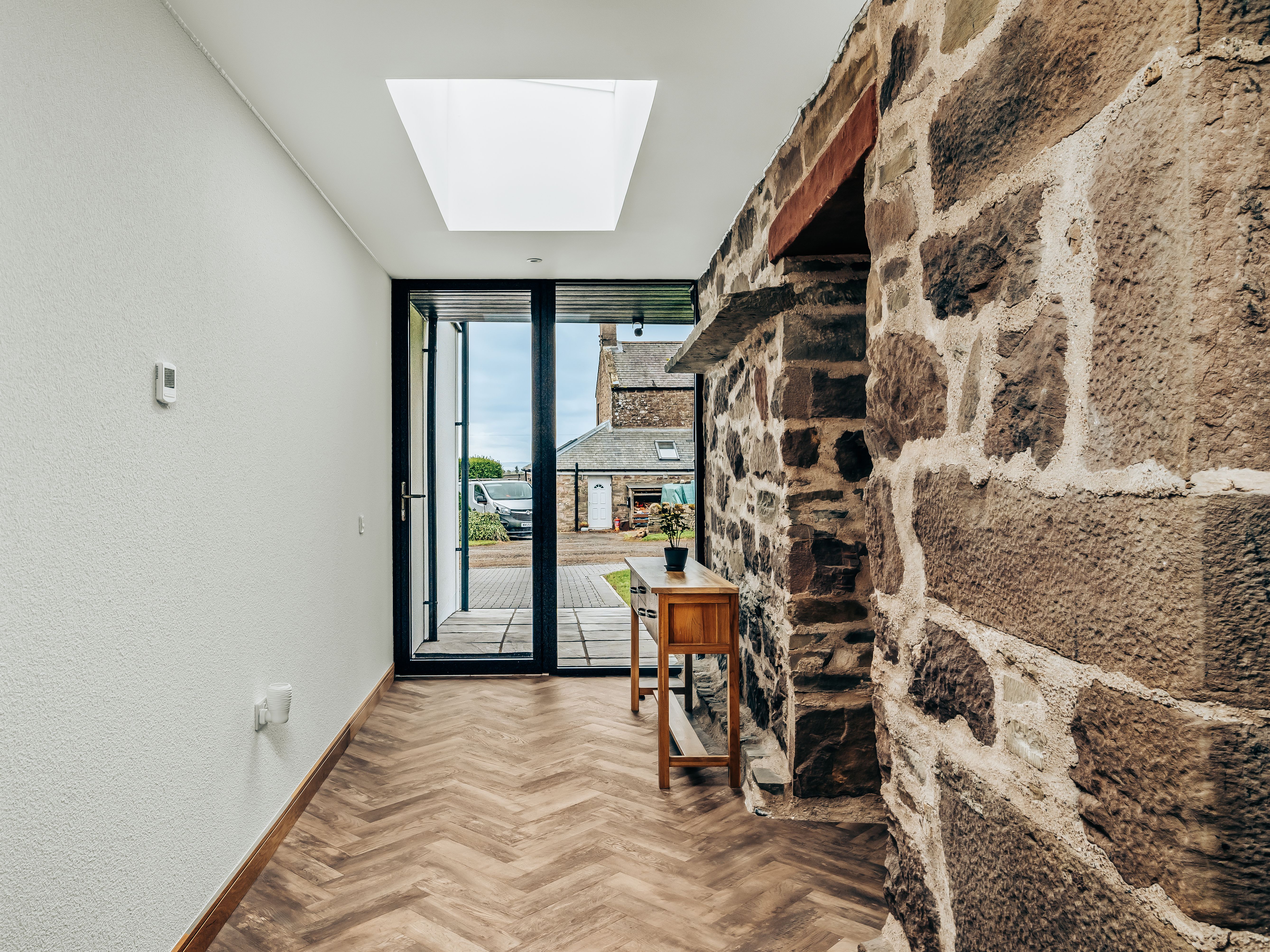 Modern hallway with stone wall, skylight, and glass door leading outside