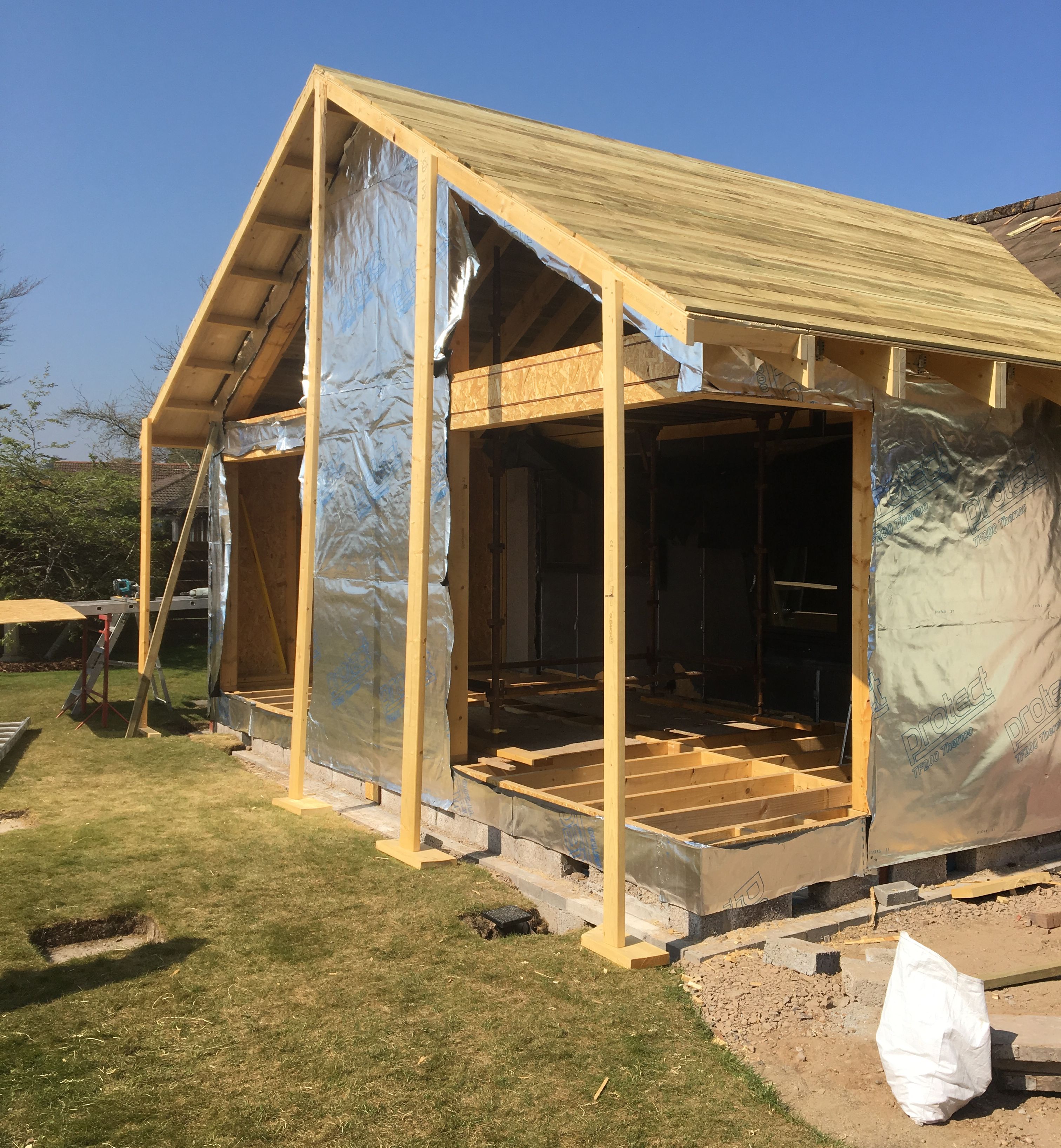 Wooden house frame under construction with reflective insulation material on the exterior