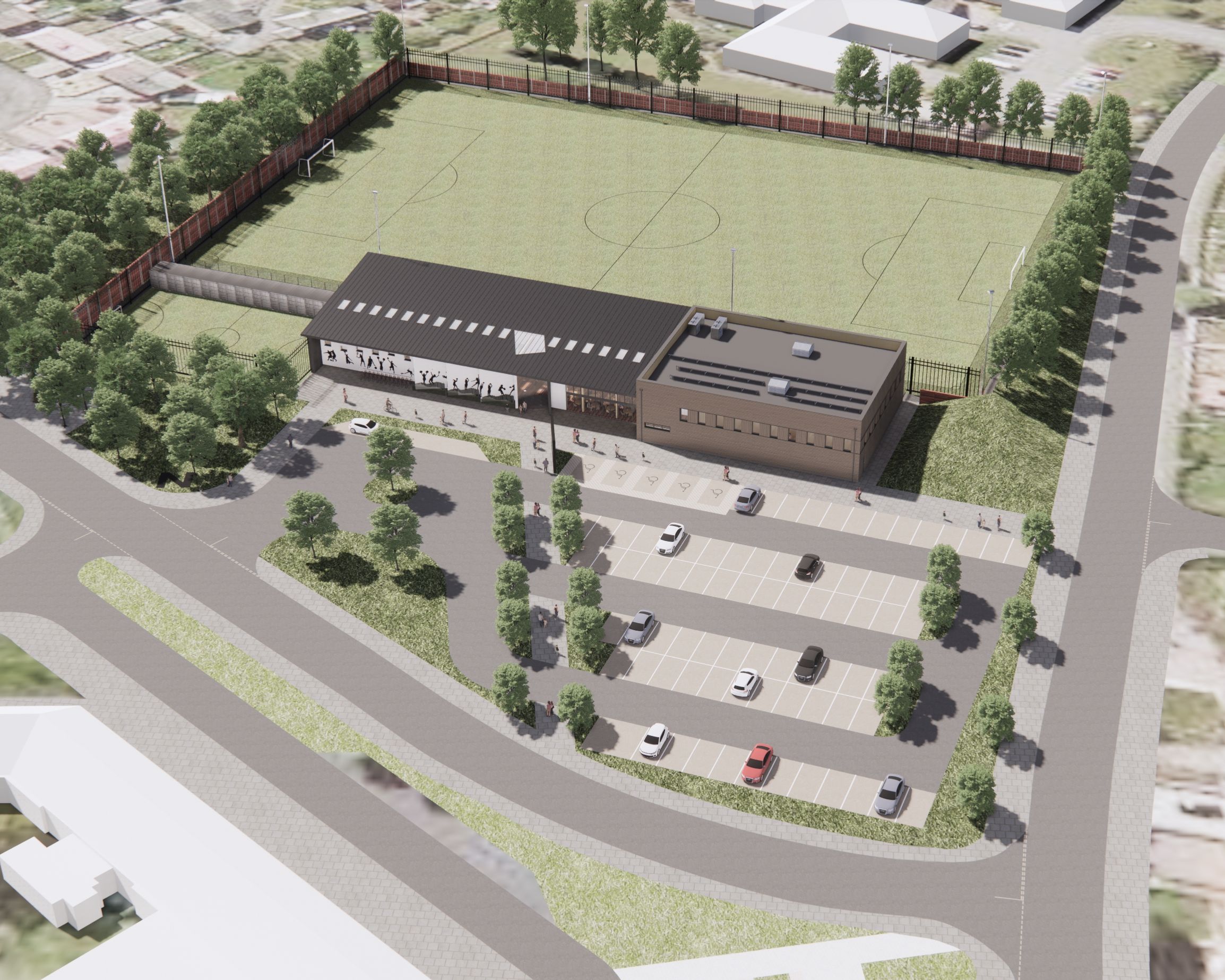 Aerial view of a sports complex with a soccer field, parking lot, and surrounding roads and buildings.