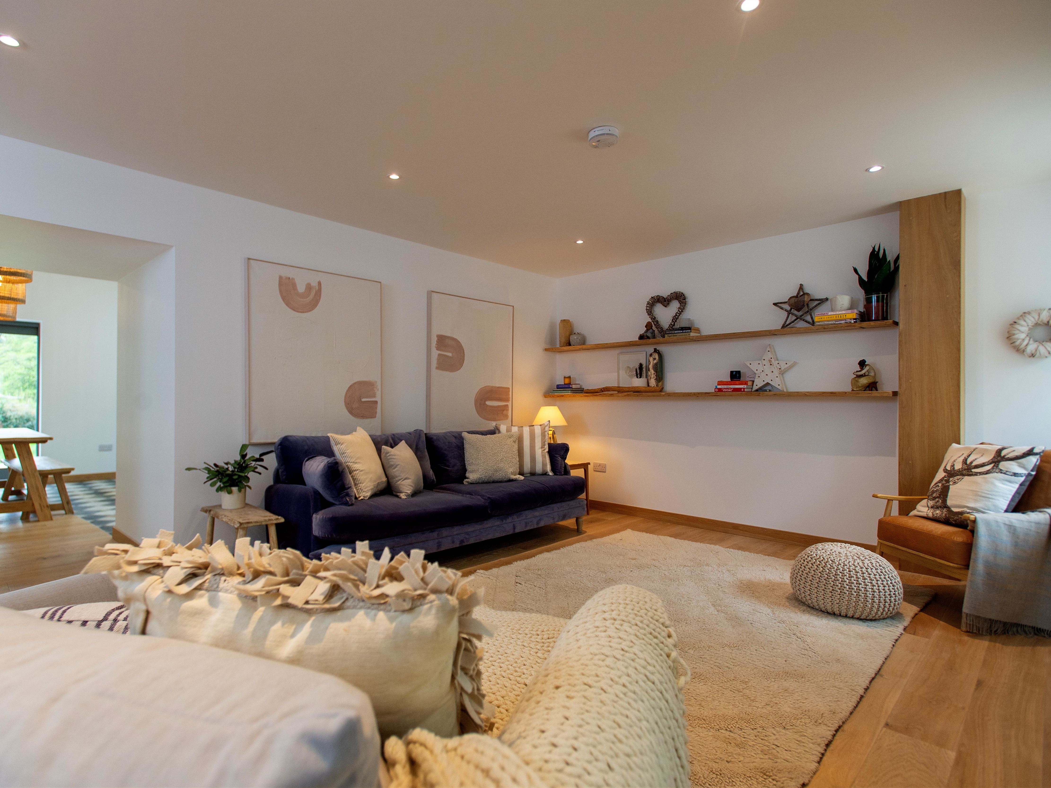 Modern living room with cozy furniture, wall art, and open shelves with decor items.