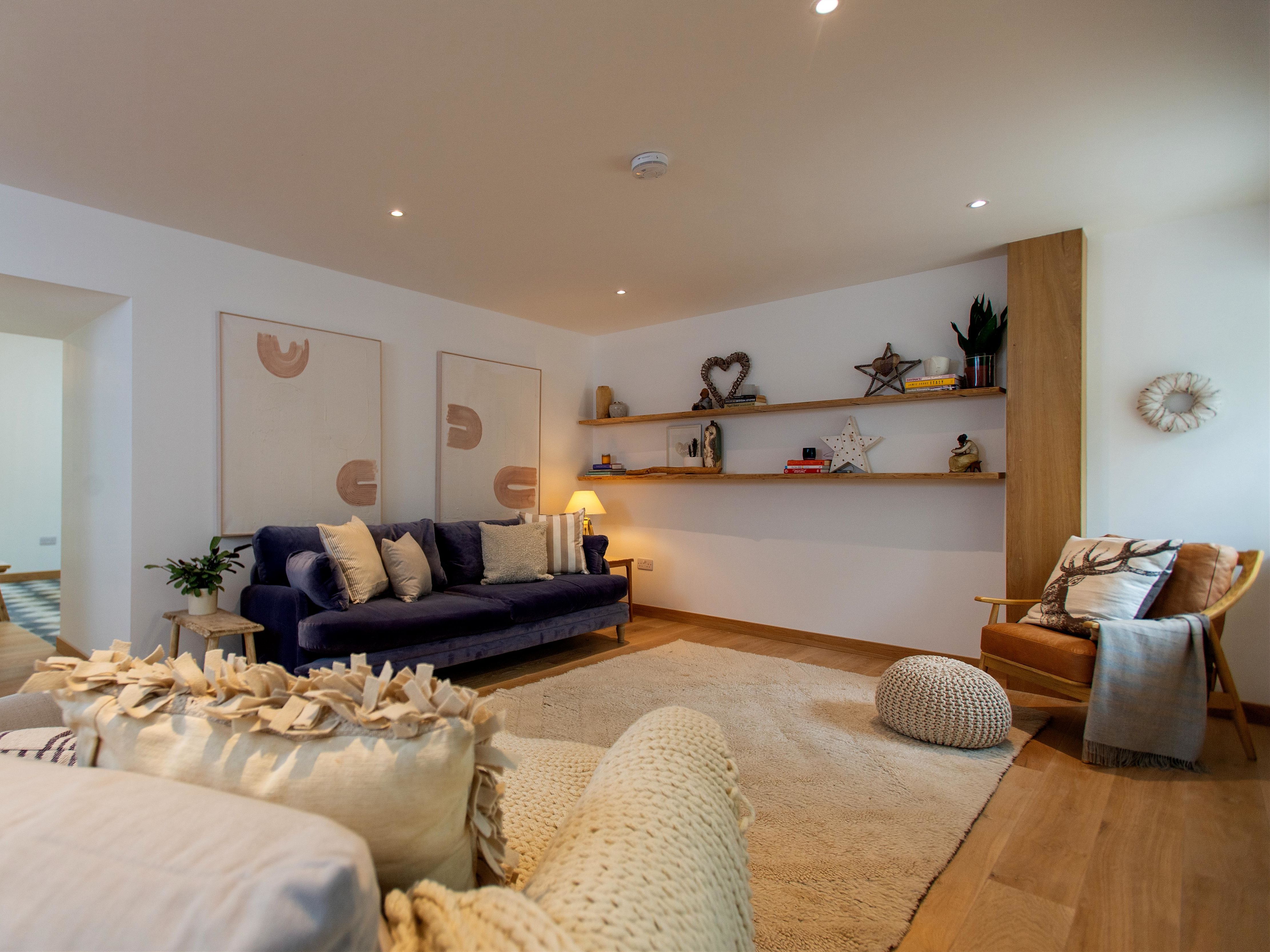 Modern living room with cozy furniture, wall art, and open shelves with decor items.