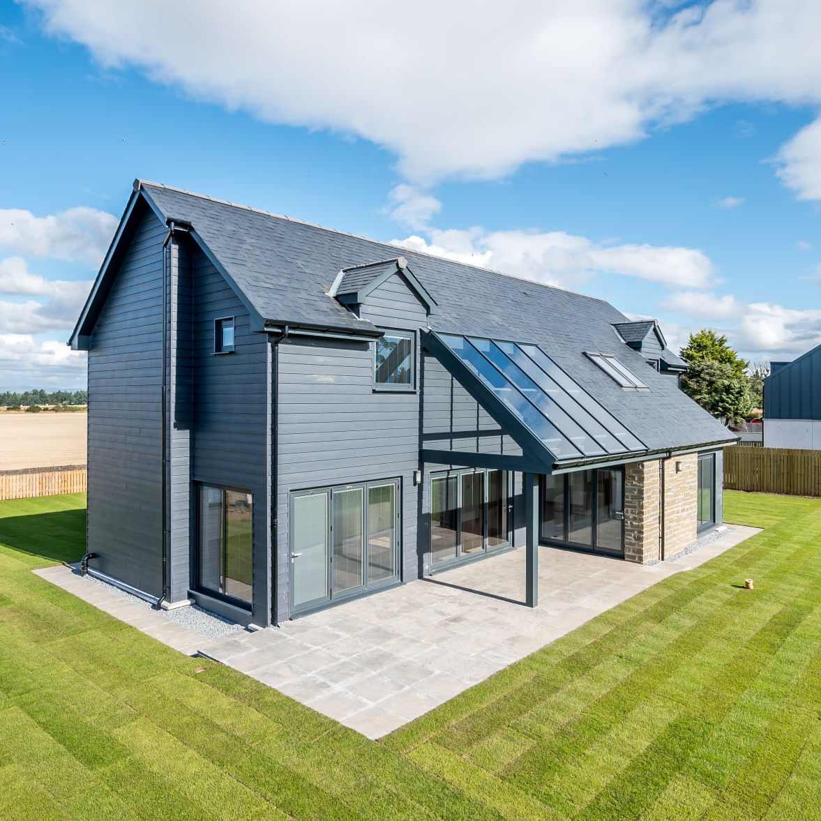 Modern two-story house with large windows and a landscaped backyard