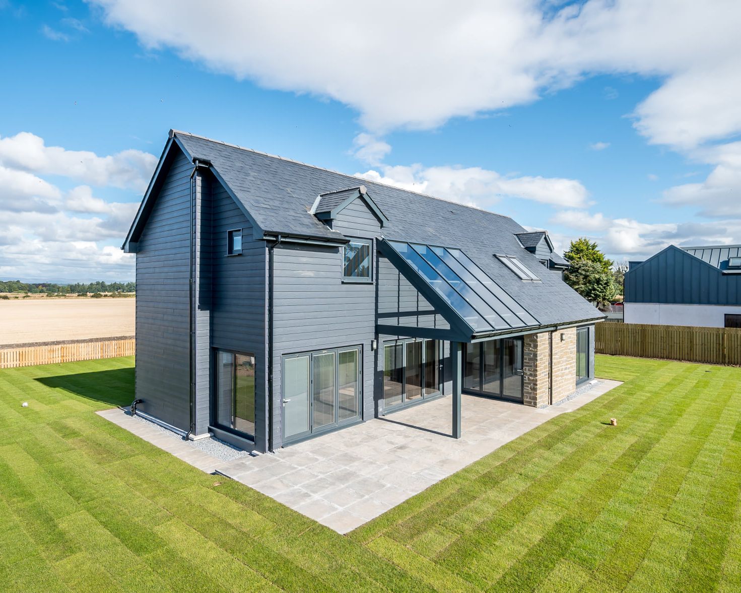 Modern two-story house with large windows and a landscaped backyard