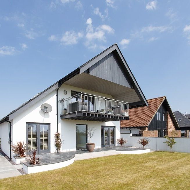 Modern white two-story house with a large balcony and sloped roof