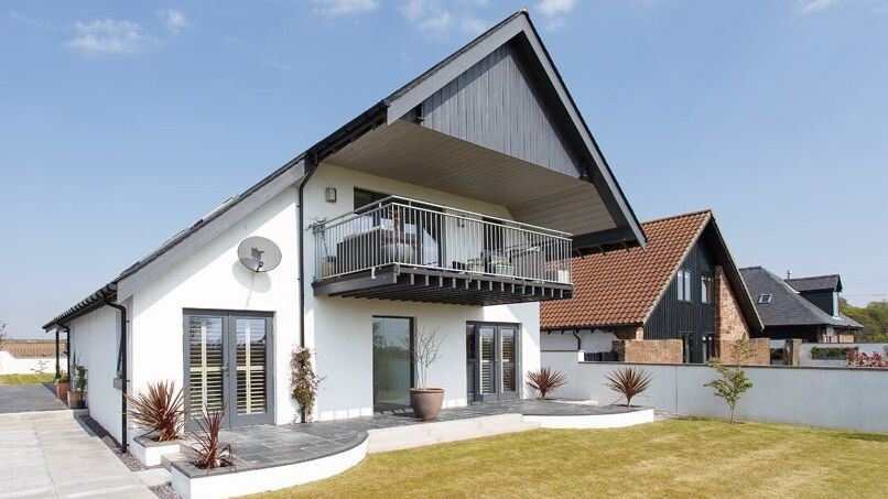 Modern white two-story house with a large balcony and sloped roof