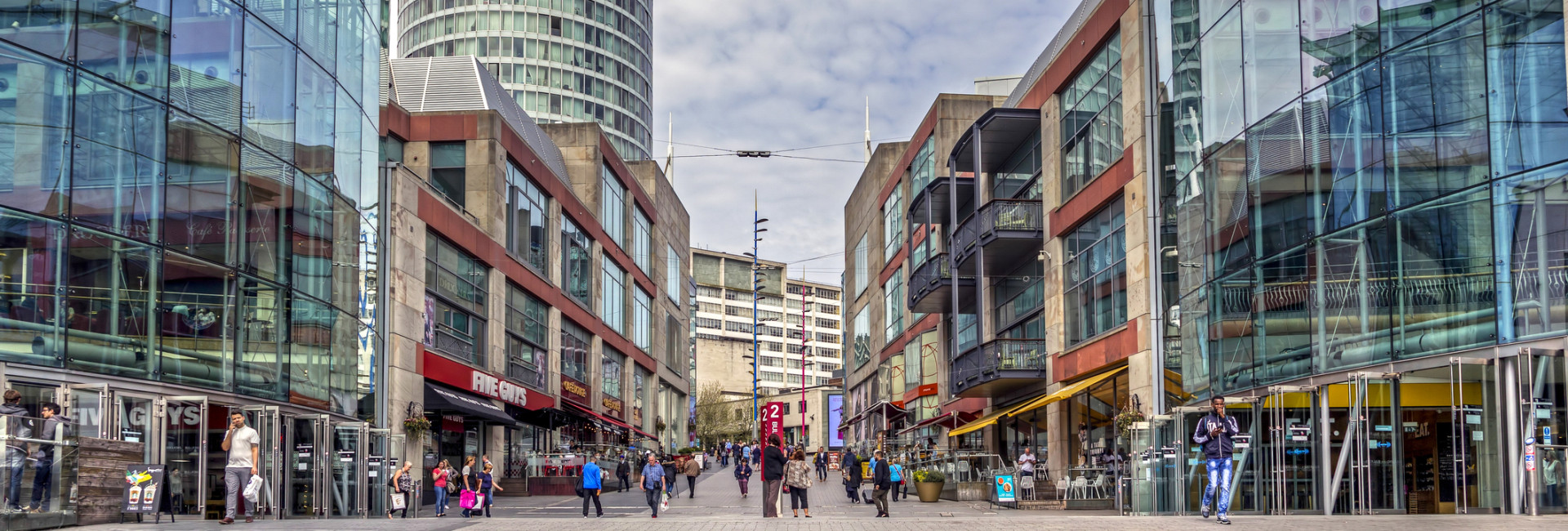 View of Birmingham's Bullring shopping area with modern glass buildings and a tower.
