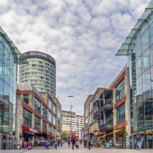 View of Birmingham's Bullring shopping area with modern glass buildings and a tower.