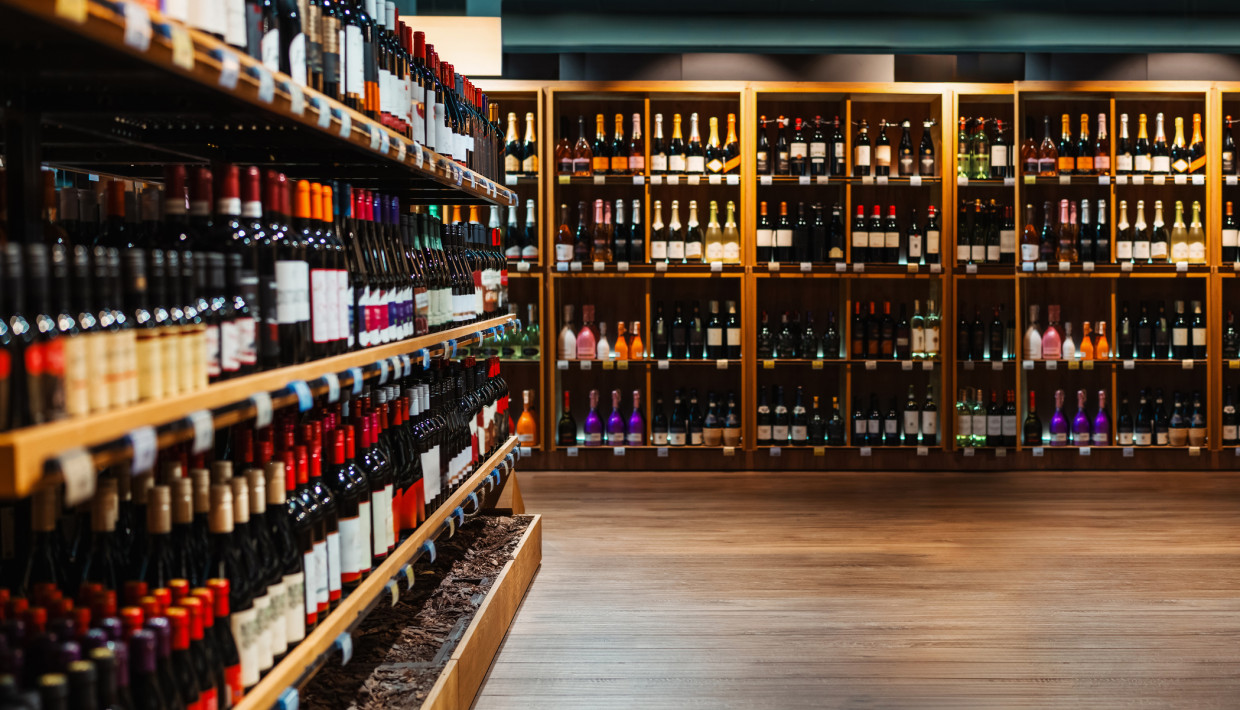 Wine selection on display in a store, with bottles organized on wooden shelves.