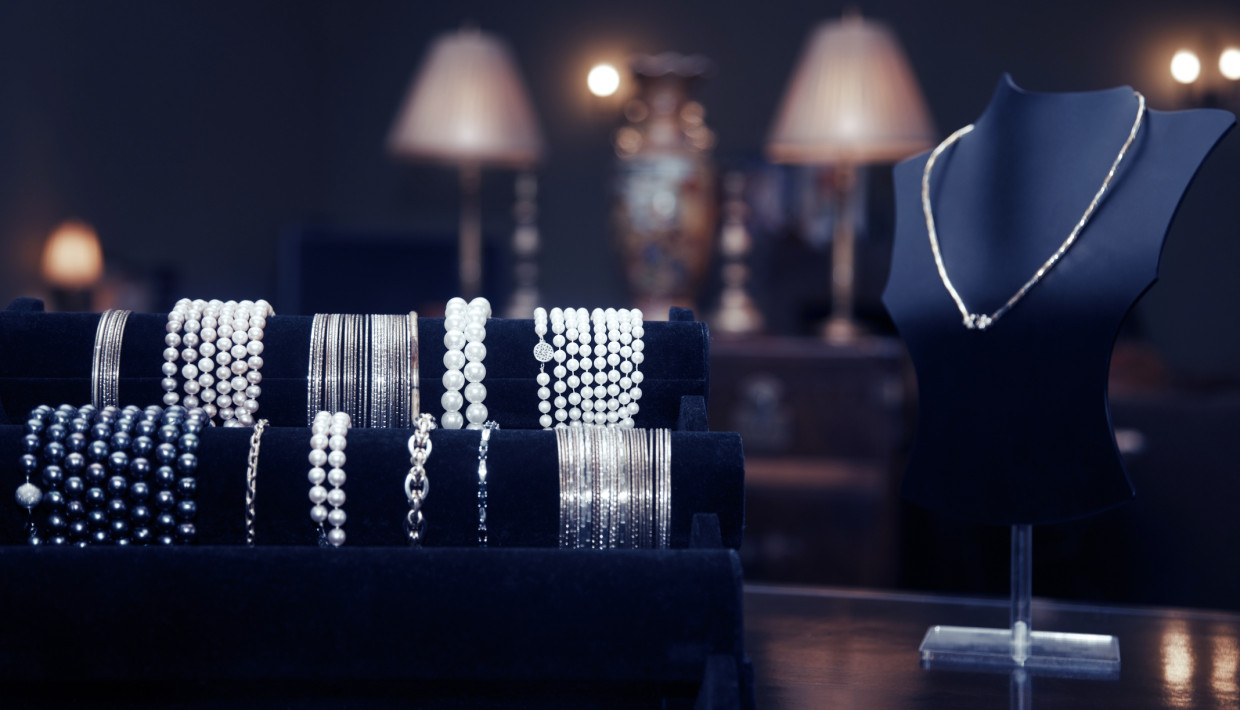 Assortment of pearl and silver jewelry on display in a dimly lit, luxurious setting.