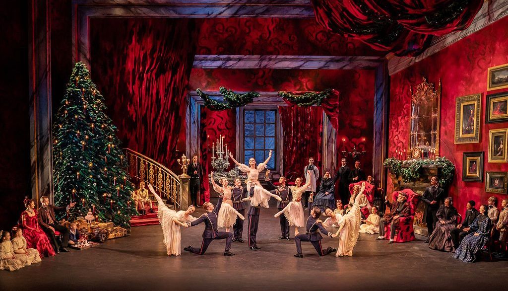 A Christmas ballet performance in Birmingham, featuring elegant dancers, a grand Christmas tree, rich red decor, and an audience dressed in period costumes, evoking holiday magic.