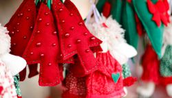 Red and green felt ornaments, including Christmas trees and hearts, displayed at a festive market stall, capture the spirit of Christmas in Birmingham with their charming holiday detail.