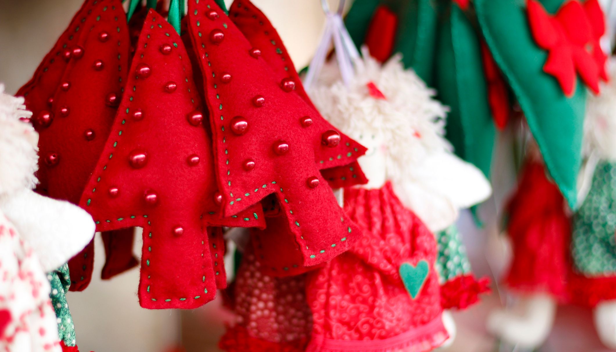 Red and green felt ornaments, including Christmas trees and hearts, displayed at a festive market stall, capture the spirit of Christmas in Birmingham with their charming holiday detail.