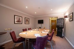 Small conference room with oval table, red chairs, and flip chart