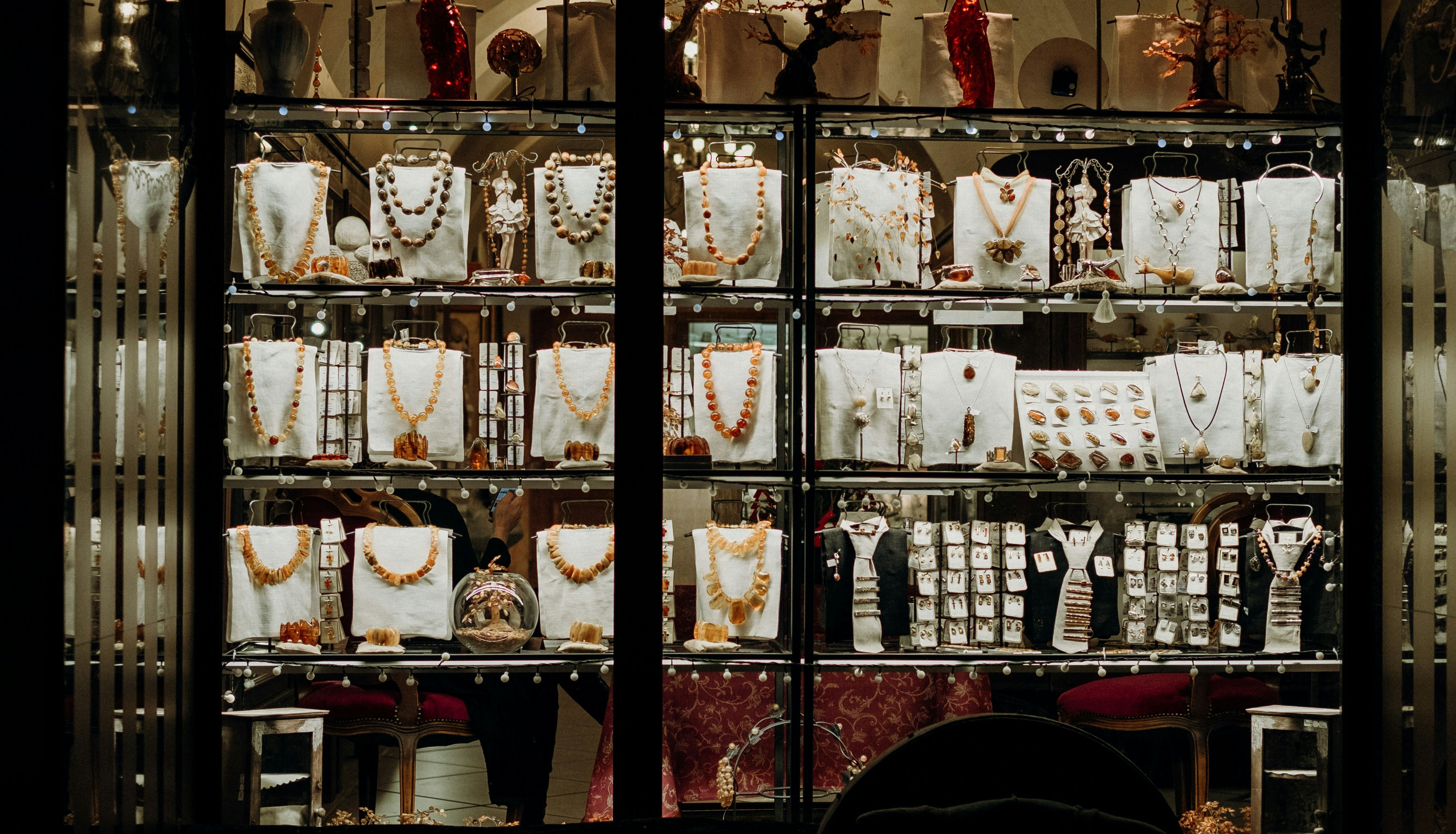 Jewelry store window display with various necklaces, rings, and earrings showcased on stands.