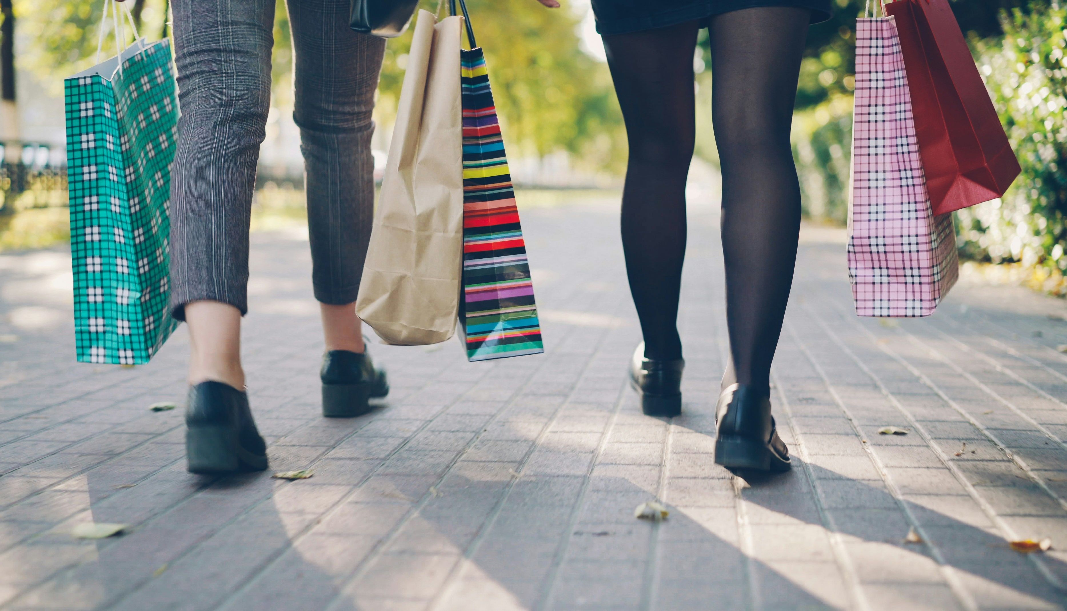Two people walking outdoors carrying colorful shopping bags