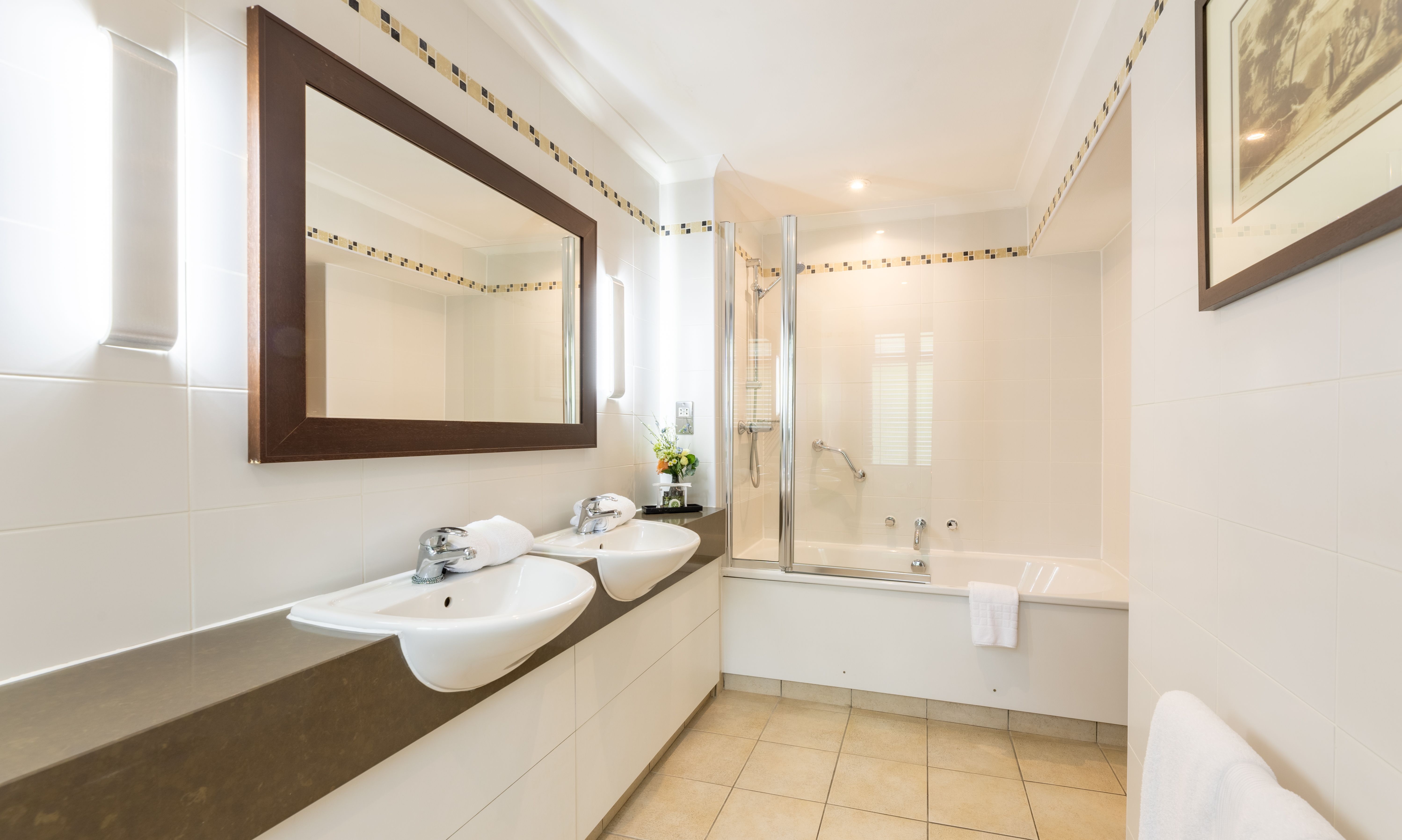 Modern bathroom with double sinks, large mirror, and bathtub with shower