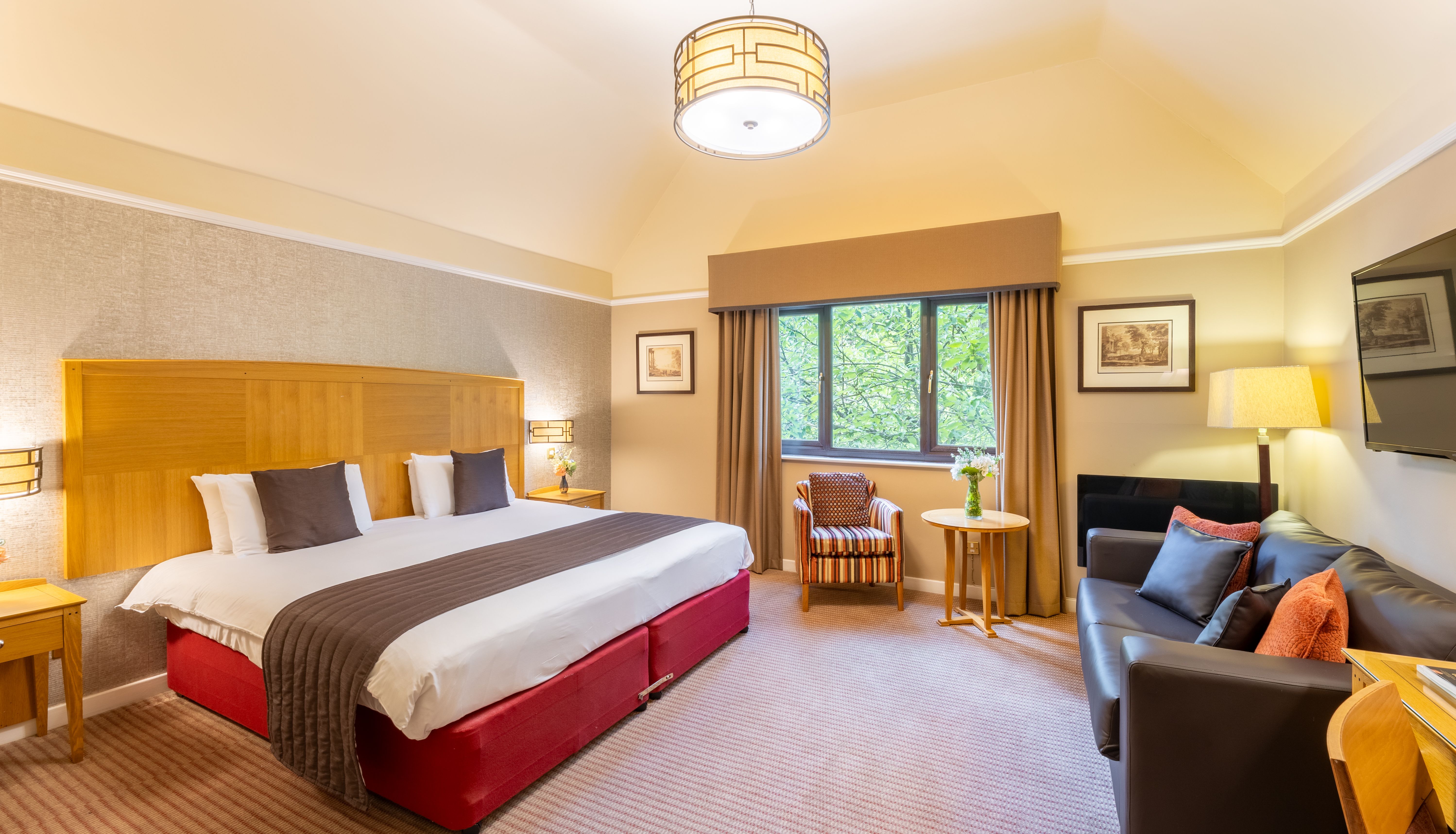 Spacious hotel suite with king-size bed, seating area, window, and modern decor