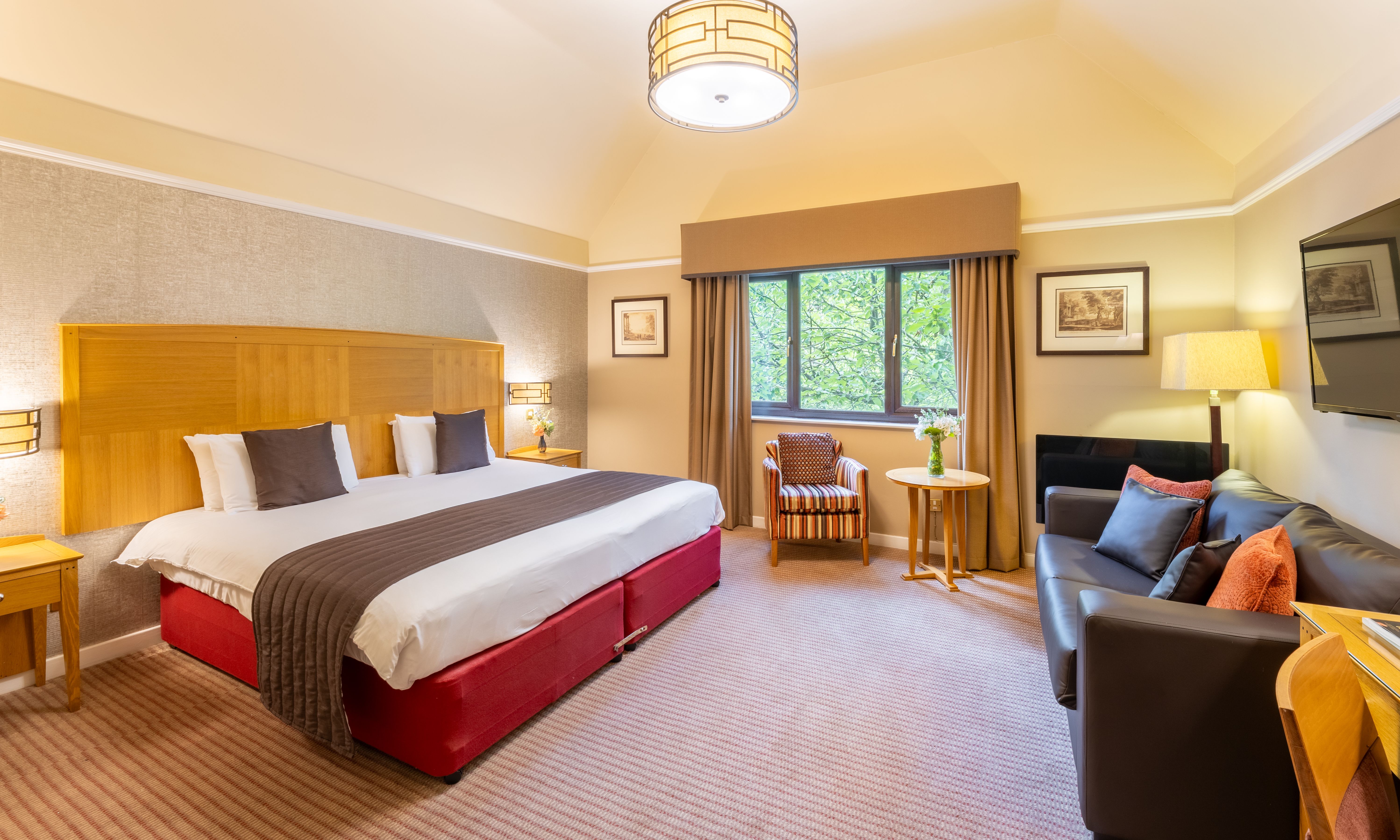 Spacious hotel suite with king-size bed, seating area, window, and modern decor