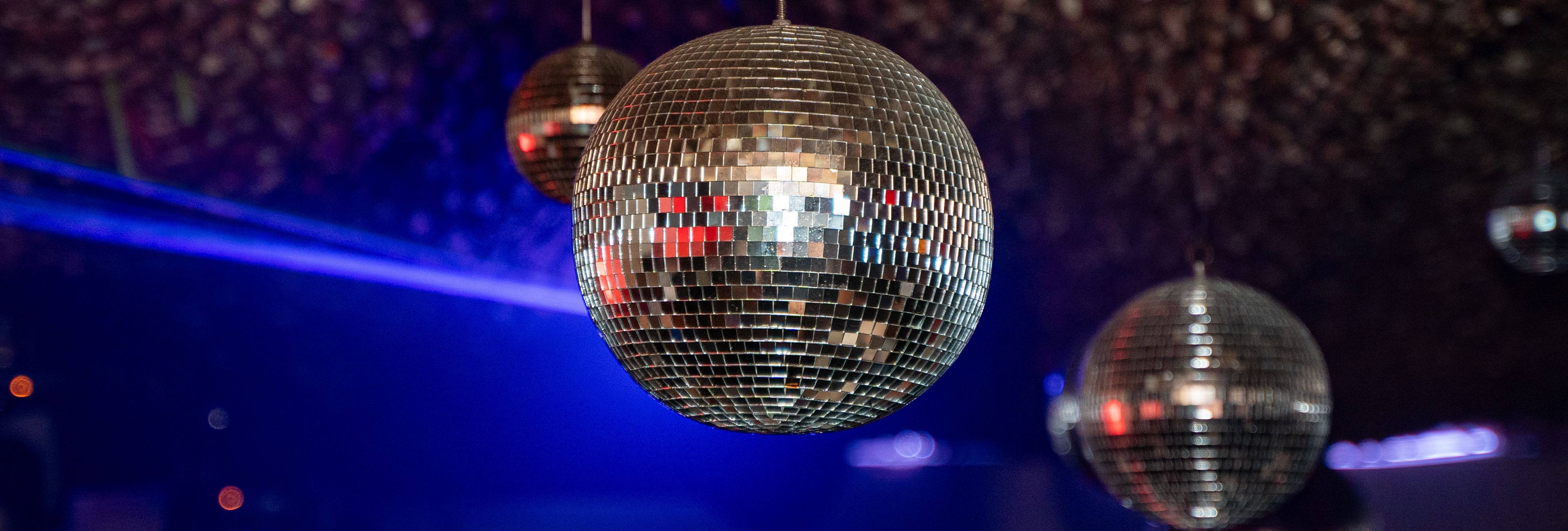 Hanging mirrored disco ball in a nightclub with blue stage lighting