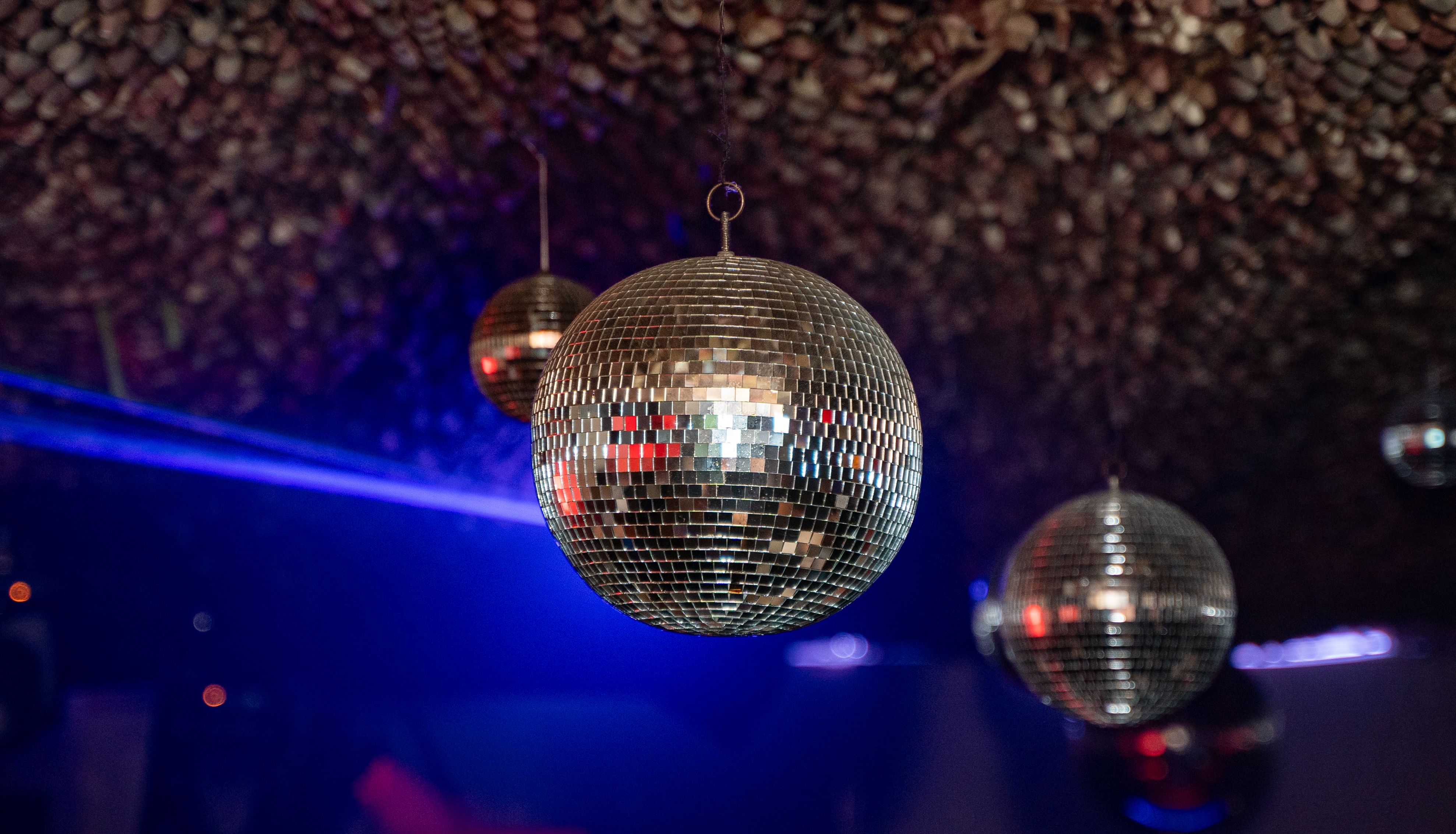 Hanging mirrored disco ball in a nightclub with blue stage lighting