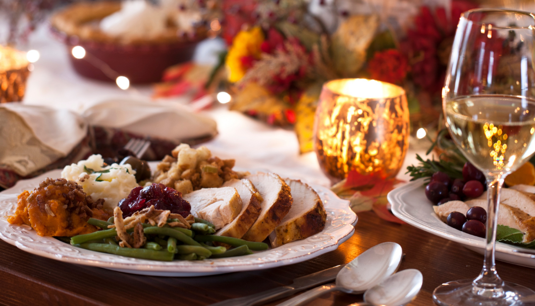 Cosy festive dinner table with turkey, cranberry sauce, candles and twinkling lights