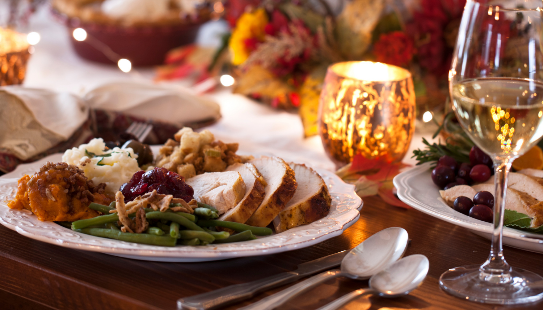 Cosy festive dinner table with turkey, cranberry sauce, candles and twinkling lights