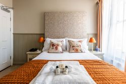 Double bed with orange throw, towels and toiletries on bed