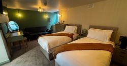Cozy hotel room with two single beds, sofa, vanity table, and dresser
