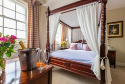 Four poster bed with bucket of champagne and glasses on table