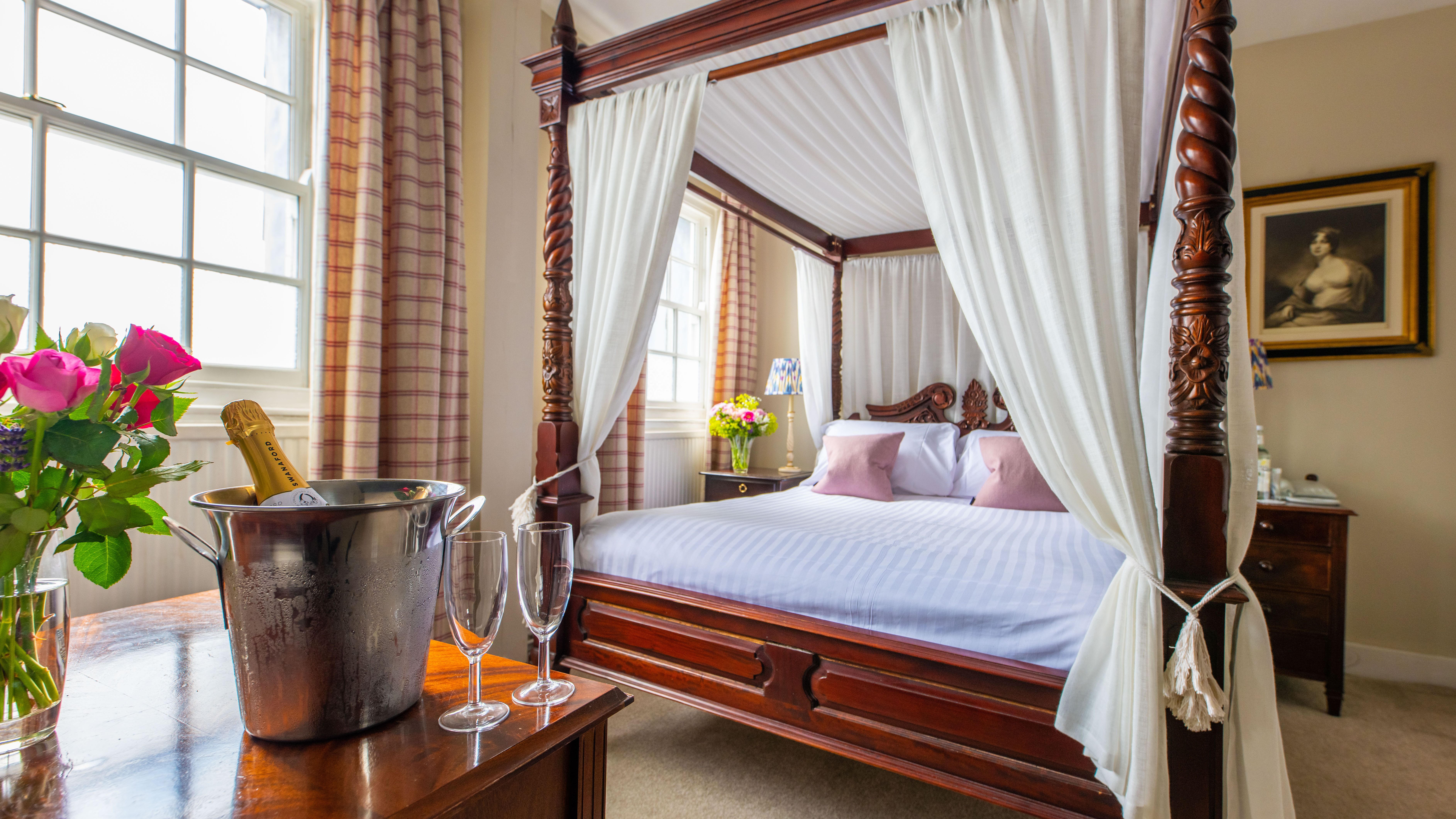 Four poster bed with bucket of champagne and glasses on table
