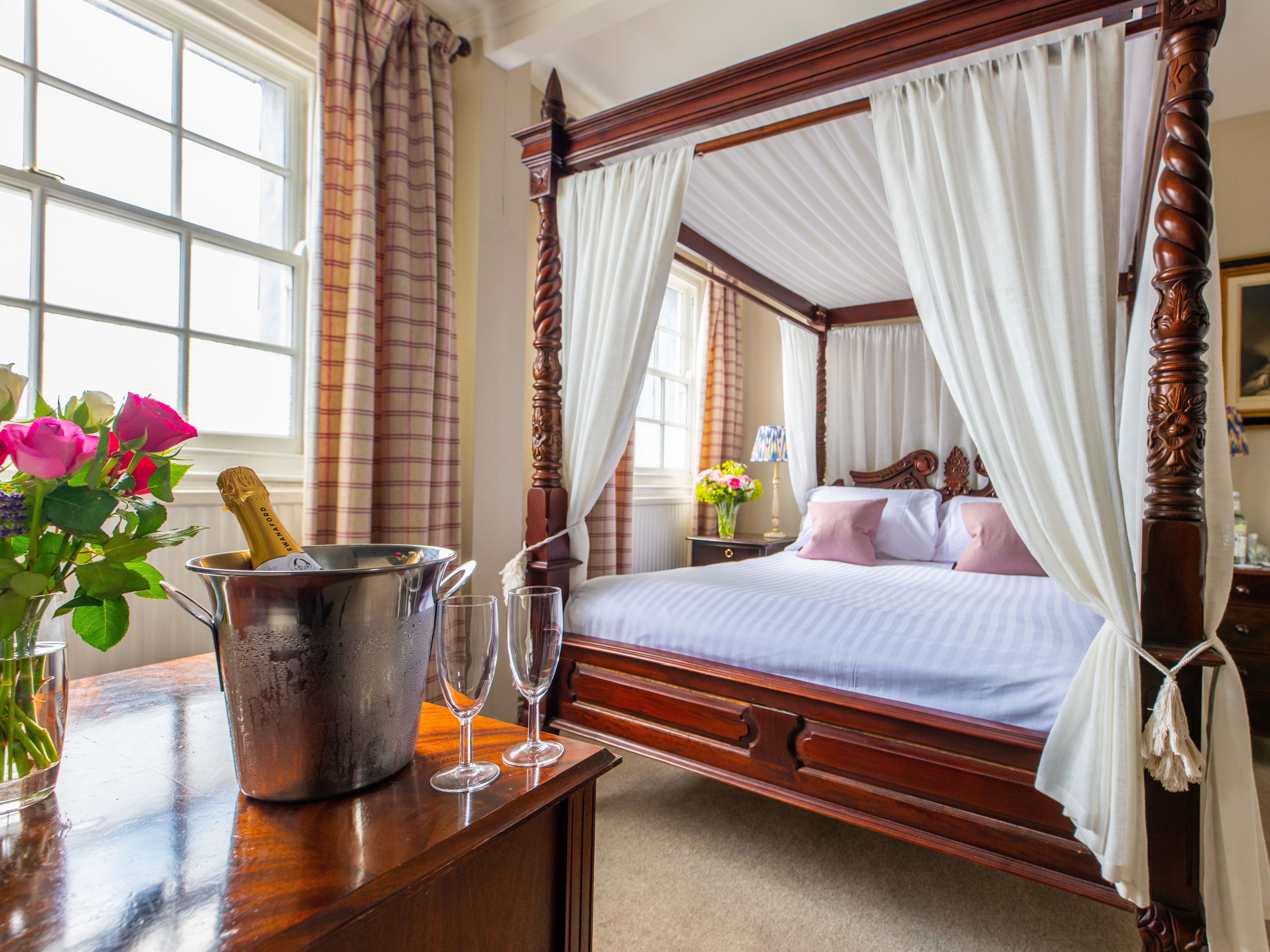 Four poster bed with bucket of champagne and glasses on table