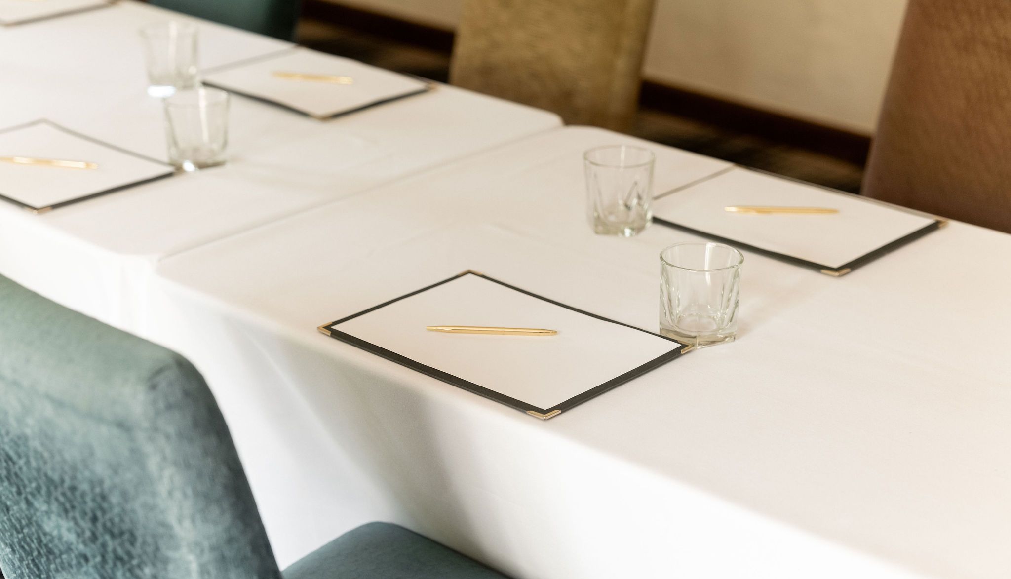 Conference table setup with notepads, pens, and glasses