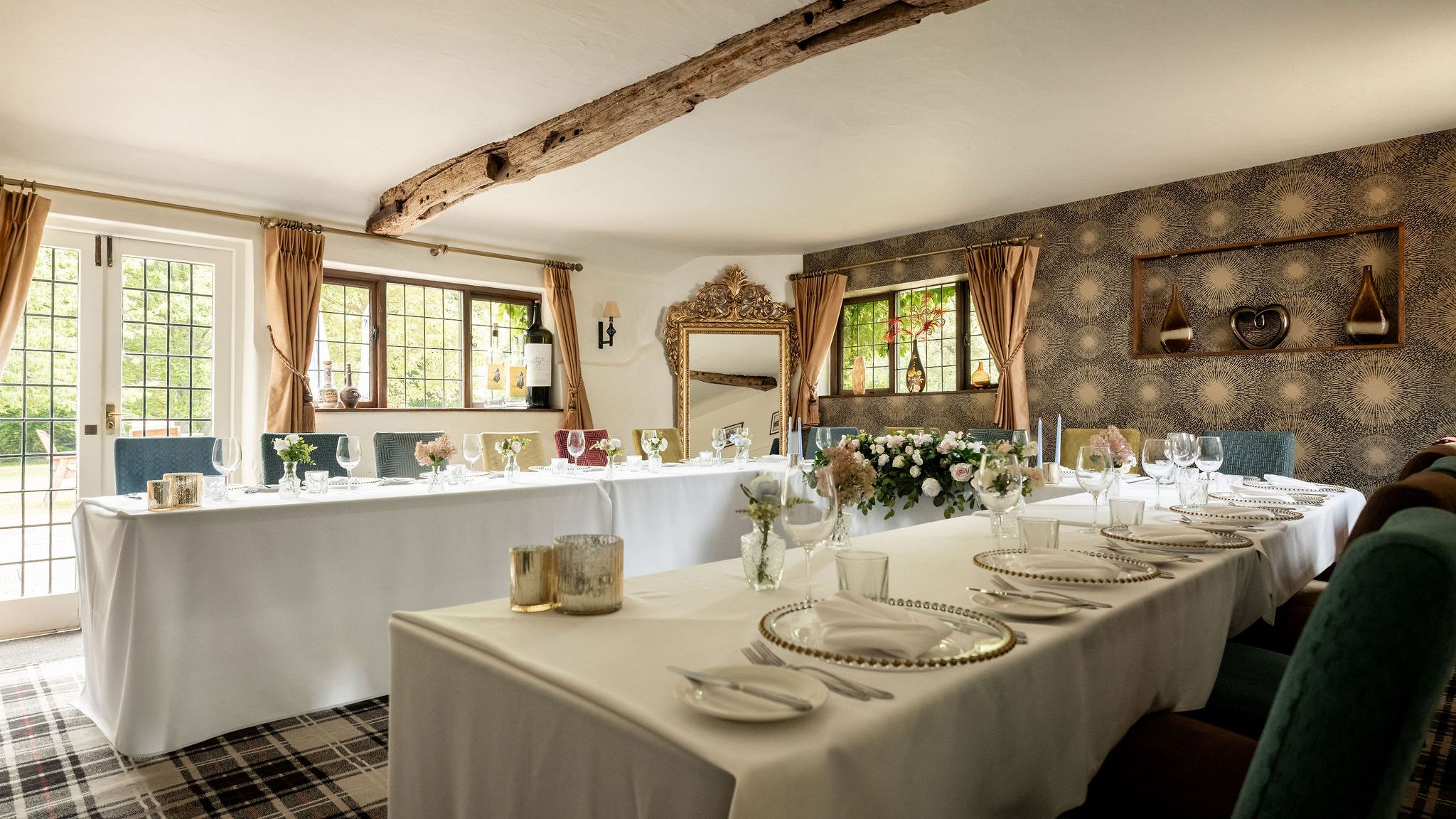 Elegant dining room setup with white tablecloths, floral centerpieces, and decorative elements in a cozy, light-filled space.